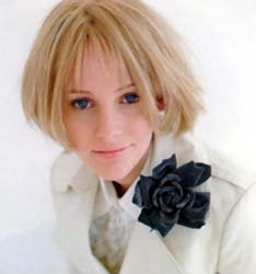 A woman with short blonde hair wearing a white tuxedo jacket