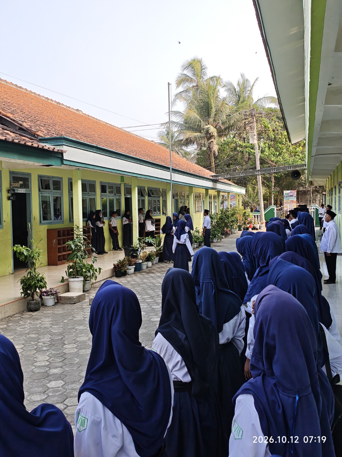 Barisan peserta didik putri berseragam rapi mengikuti prosesi upacara di halaman madrasah