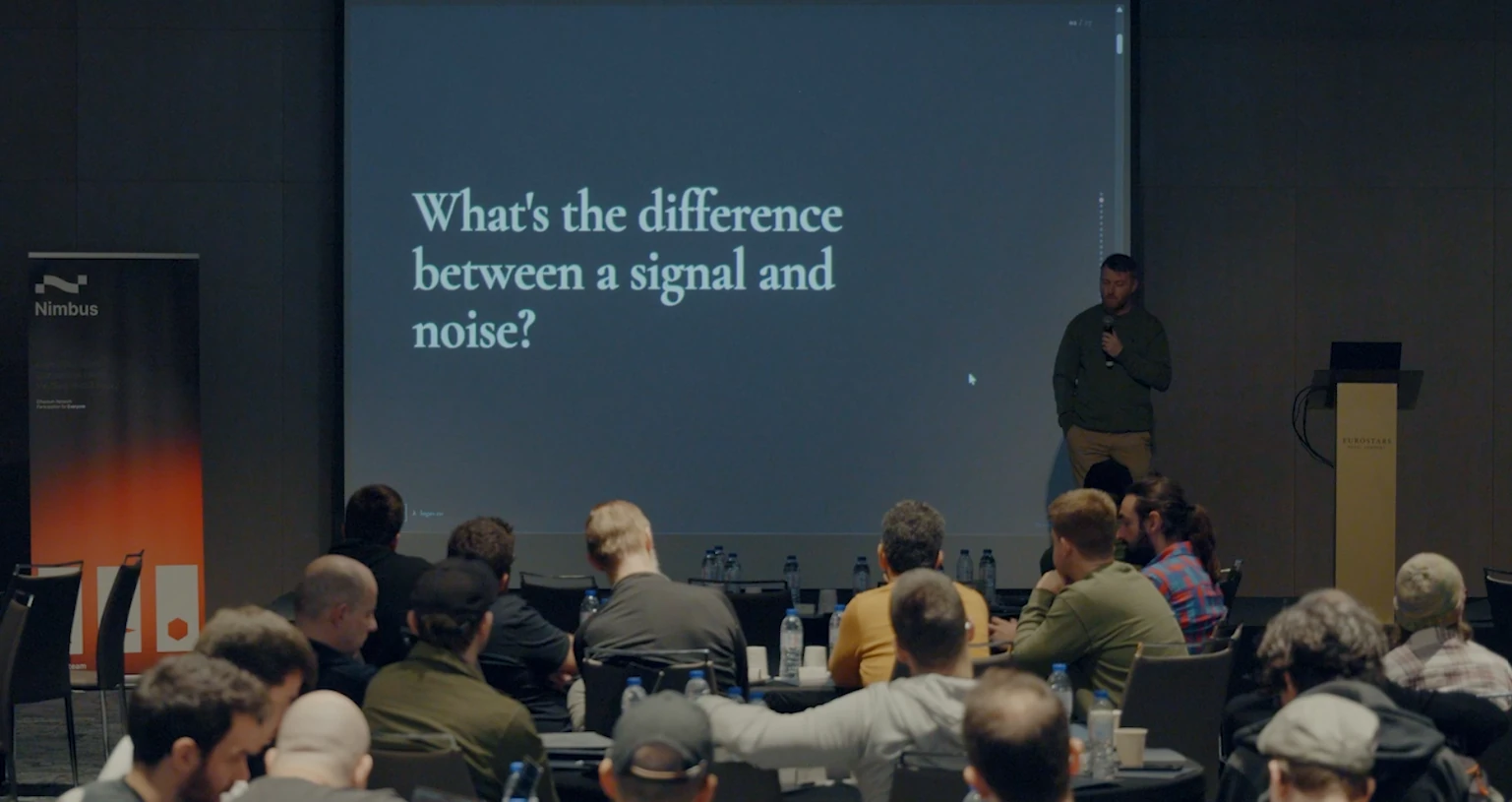 Wide auditorium view at IFT with a slide asking What's the difference between a signal and noise