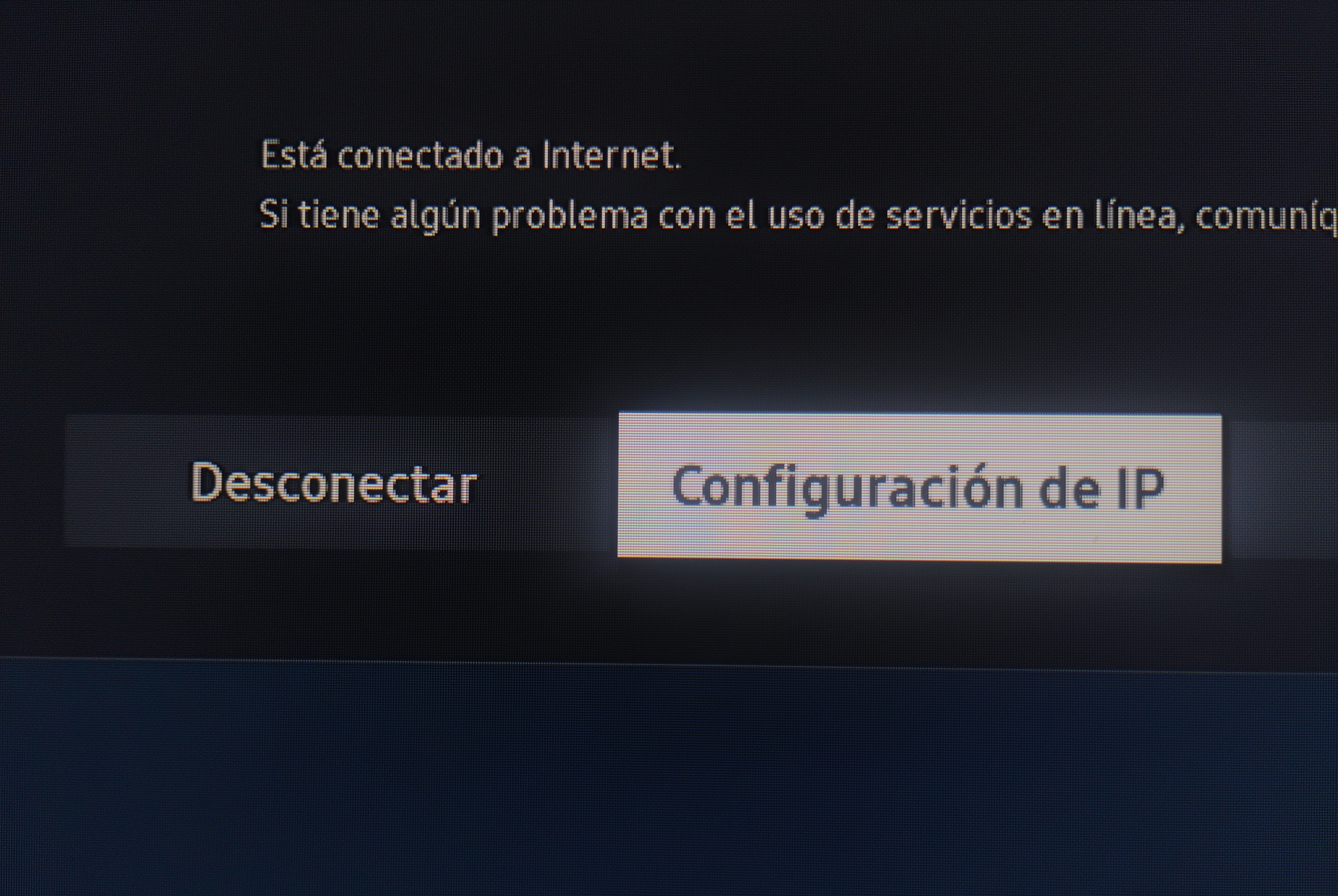 Una interfaz de usuario digital muestra información de conexión a Internet y opciones. En una pantalla oscura, dos líneas de texto aparecen arriba, y dos botones rectangulares se ubican en el centro. El botón derecho está resaltado. El texto es blanco; los botones son gris claro y beige claro. En el botón derecho 