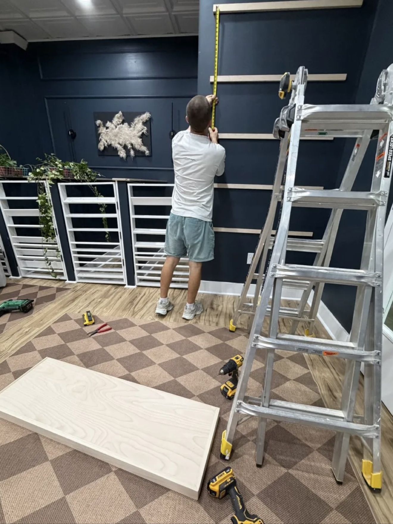 Aleh measuring a dark painted wall with a tape measure