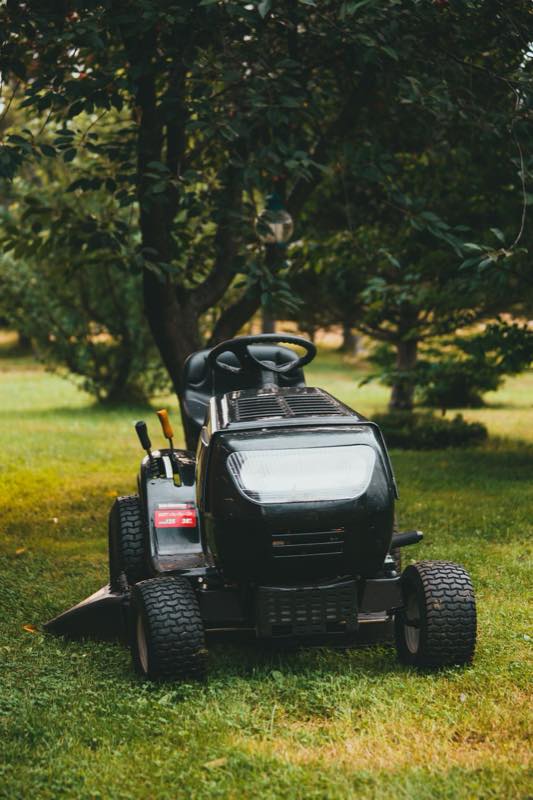 Tondeuse autoportée garée dans un jardin arboré