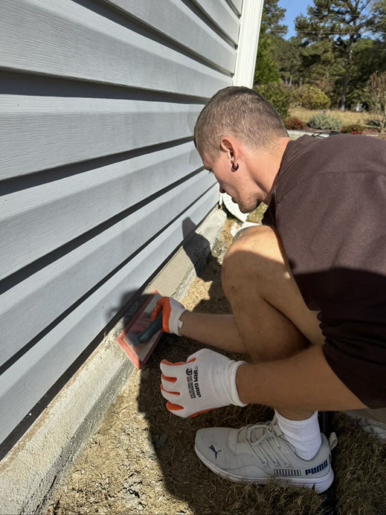 Aleh sanding the foundation trim outside, by the siding