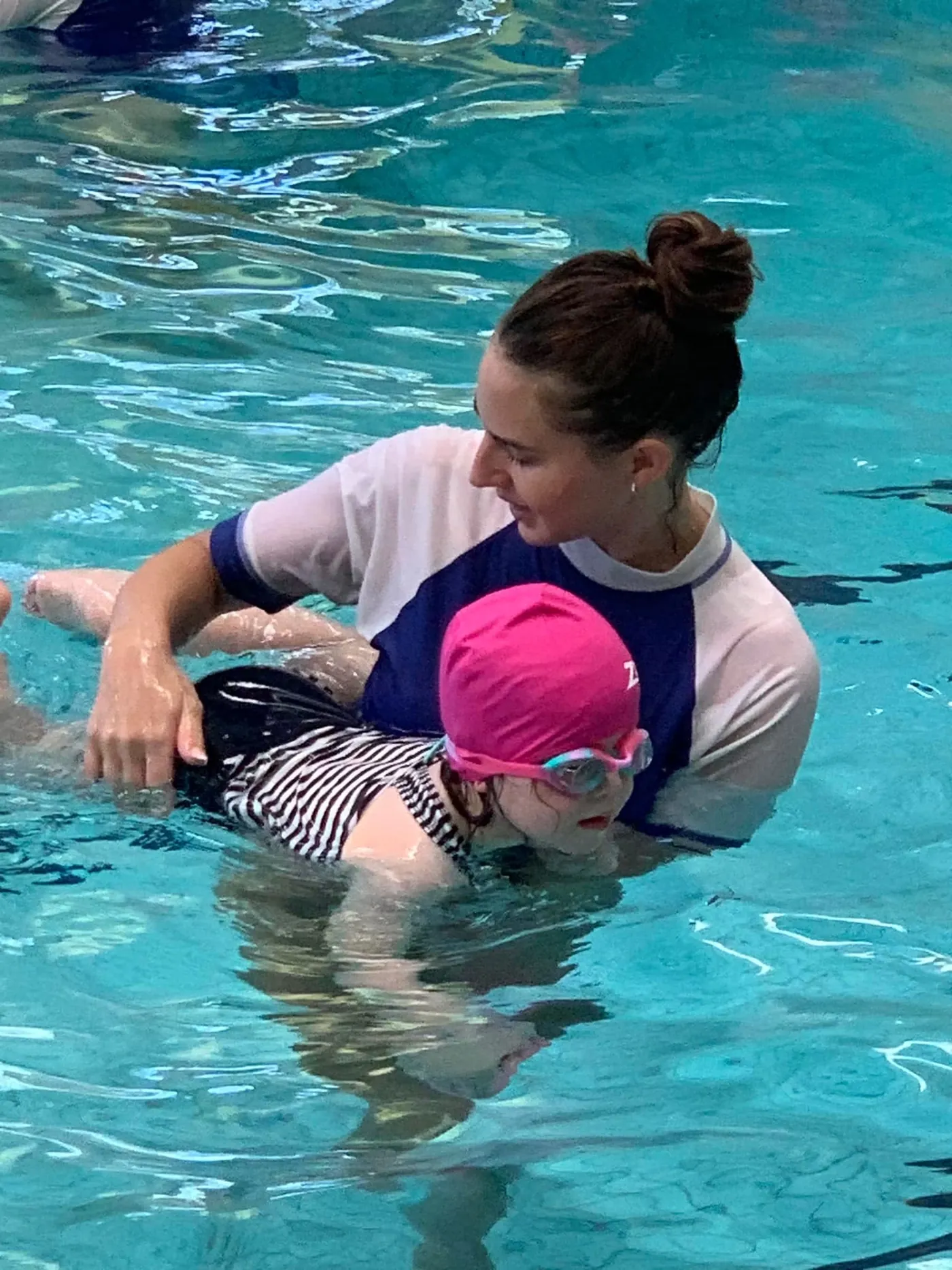 A Pod Squad instructor giving one-to-one support to a young swimmer during a lesson