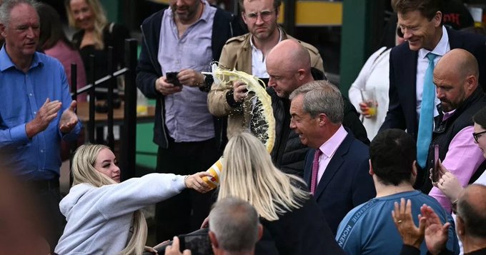 Nigel Farage in a crowd having milkshake thrown on him