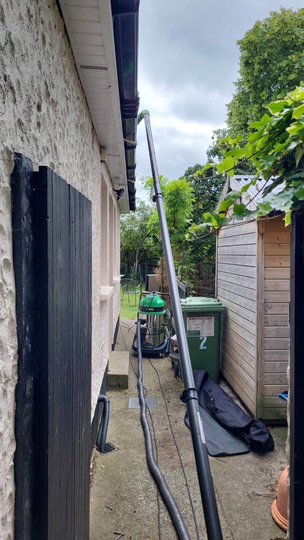 Gutter vacuum hose set up along a house exterior