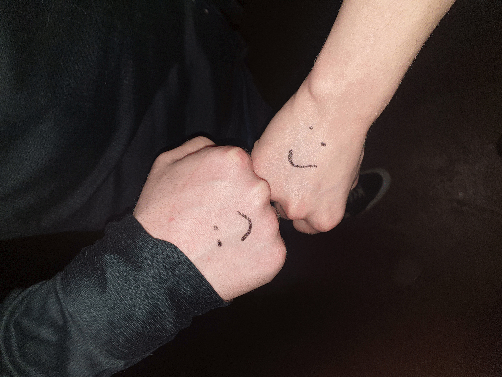 two hands fistbumping, with smiley faces drawn on