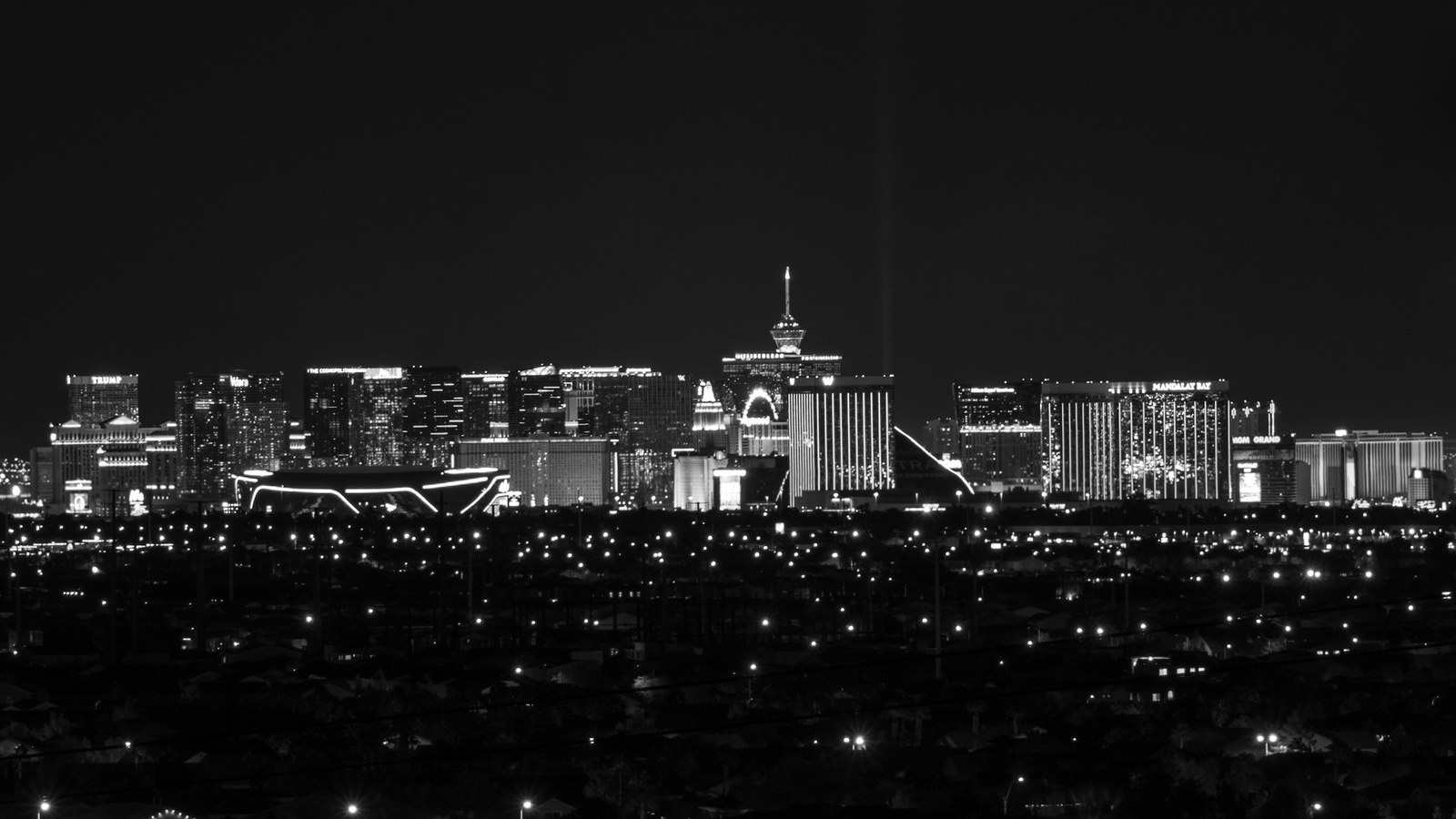 The Las Vegas Strip glows at night beneath a dark desert sky, seen from a distance.