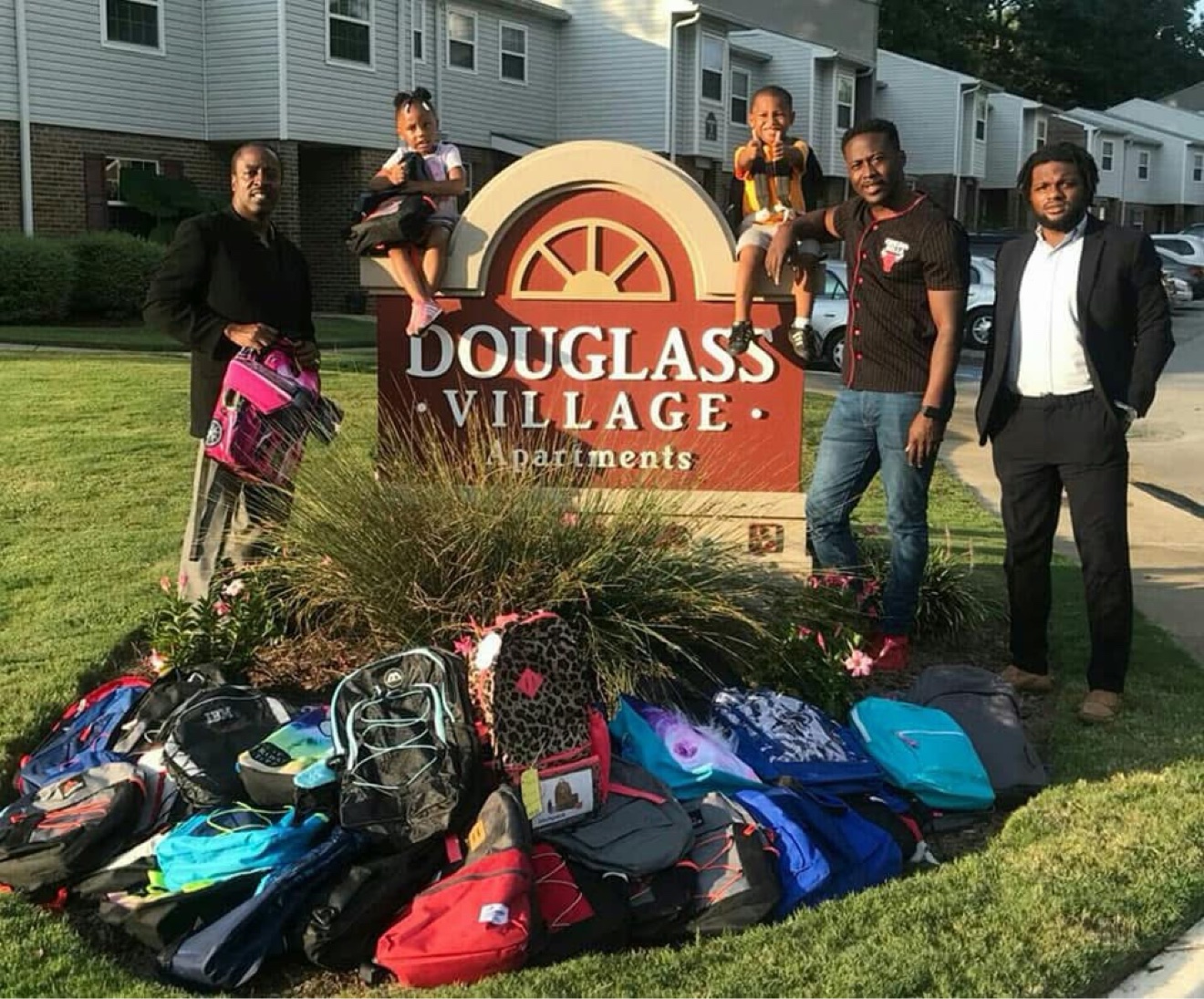 Commissioner Mitchell's team with families and donated book bags at the Douglass Village Apartments giveaway