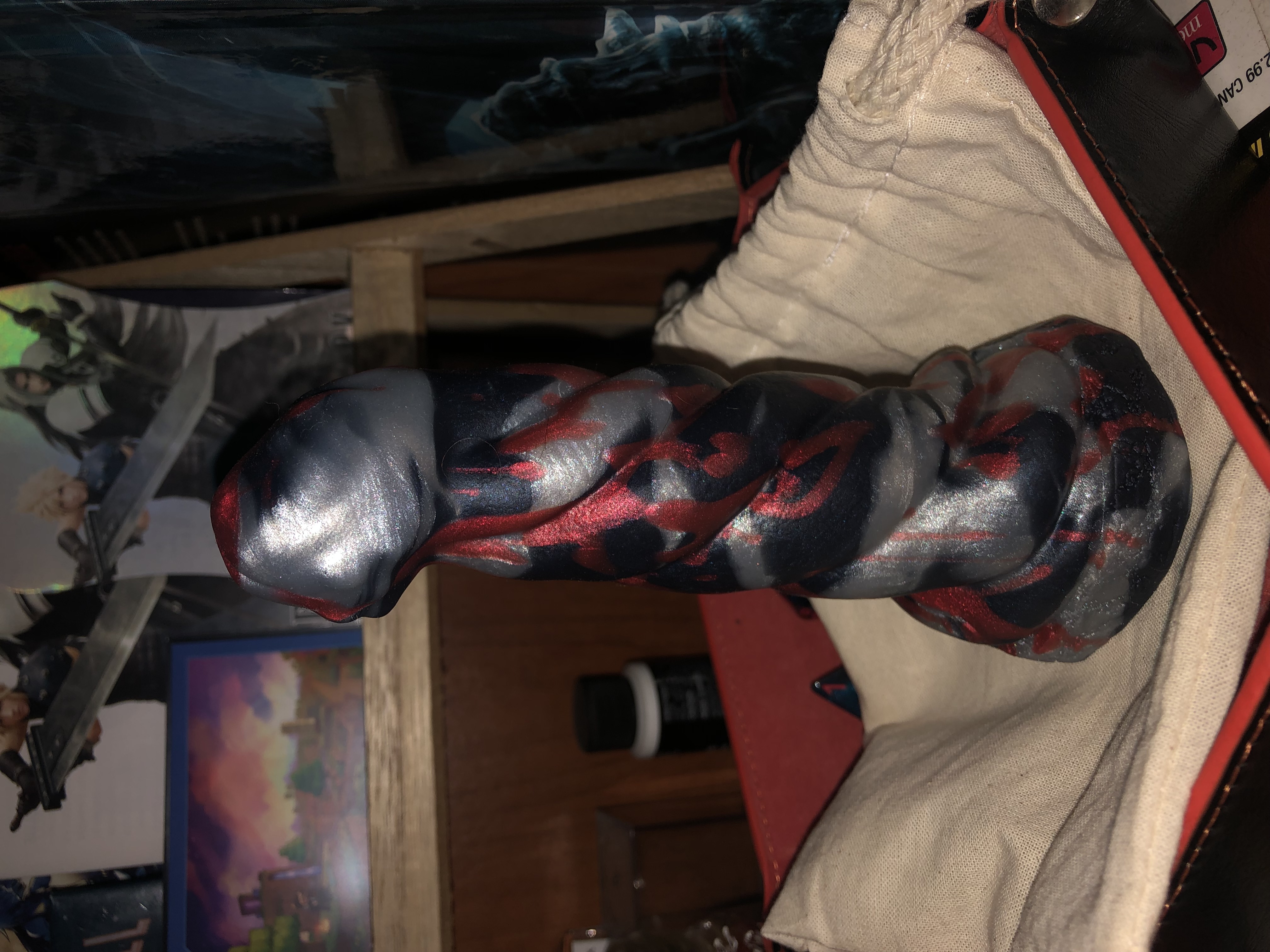 a photo of my custom mind flayer in a leather dice tray. it is silver and black marbled with red splatter.