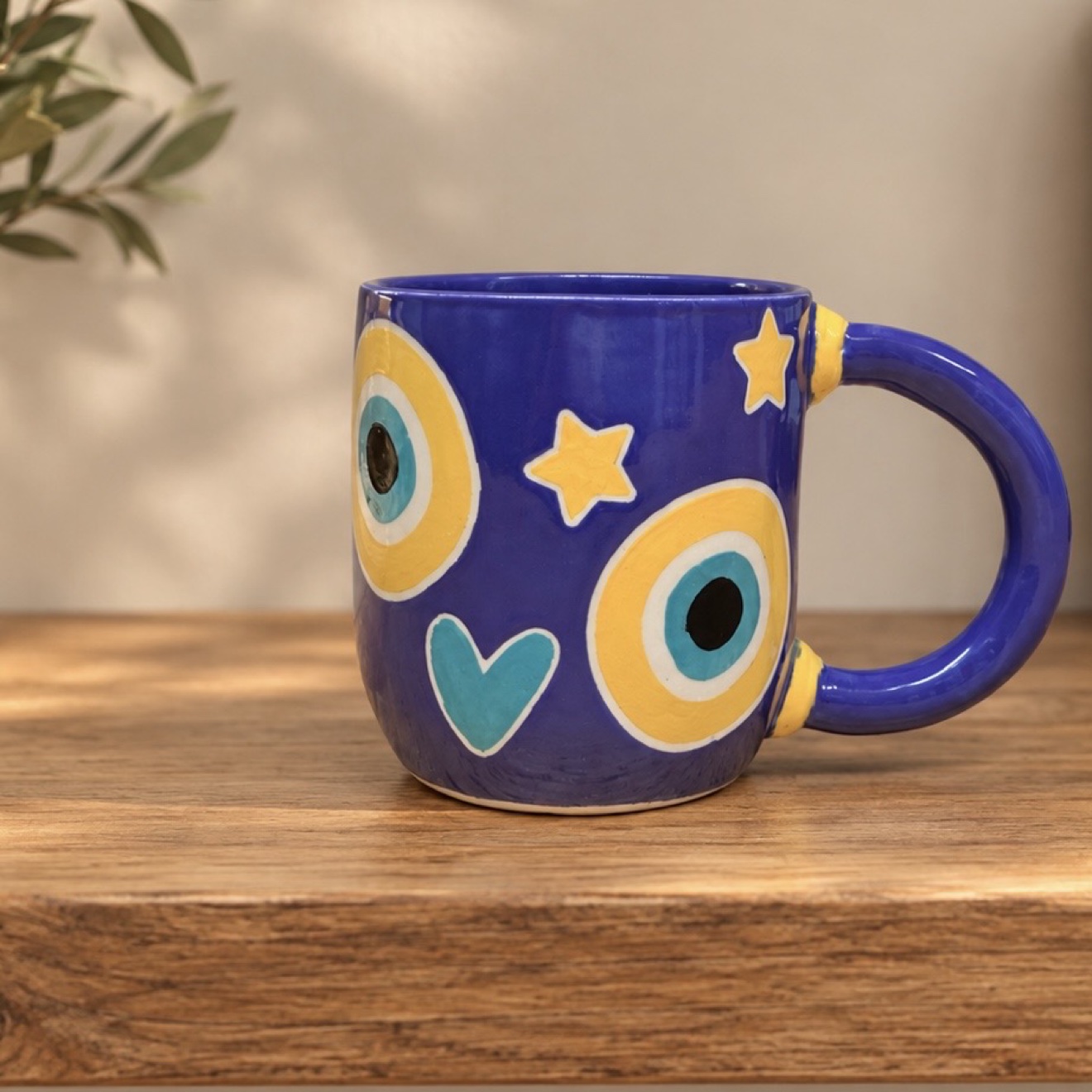 Hand-built mug with a hand-painted evil eye motif.
