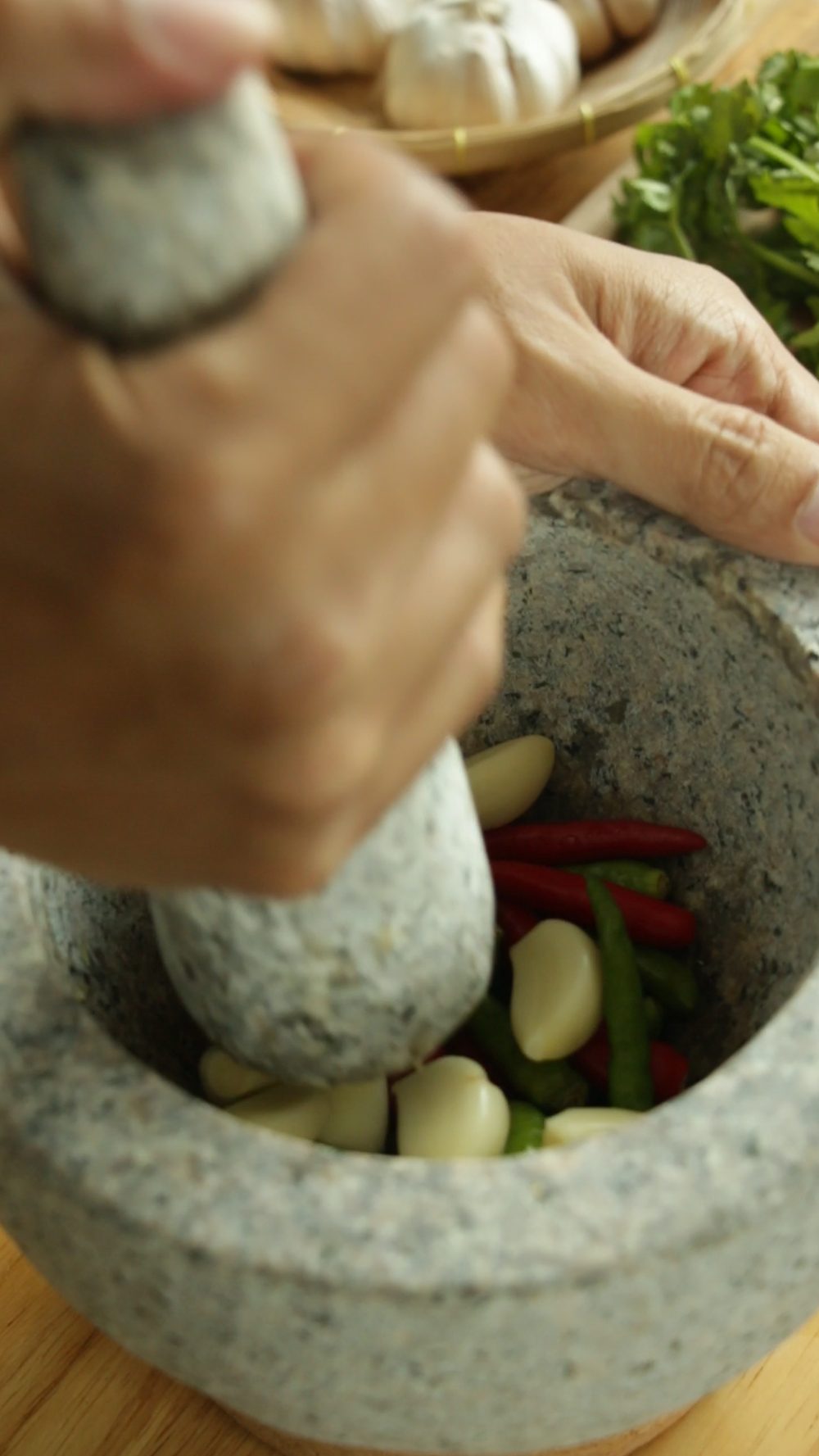 Pounding chilies and garlic in a Thai granite mortar and pestle