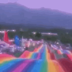 A dreamcore-themed gif of someone going down a rainbow slide 