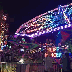 A gif of a carnival ride flashing bright colors, it happens at night.
