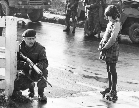 Jewish schoolgirl with a bob cut staring expectantly at guy in gun and a beret