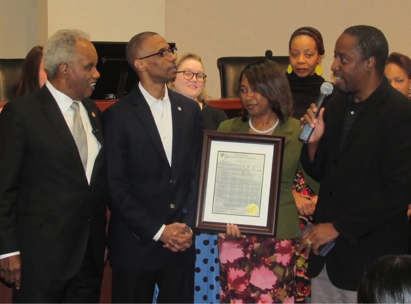Commissioner Mitchell presenting a county proclamation to community members