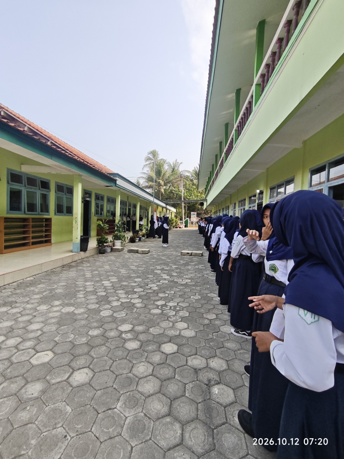 Barisan panjang murid madrasah berdiri tertib di antara gedung ruang kelas saat upacara berlangsung
