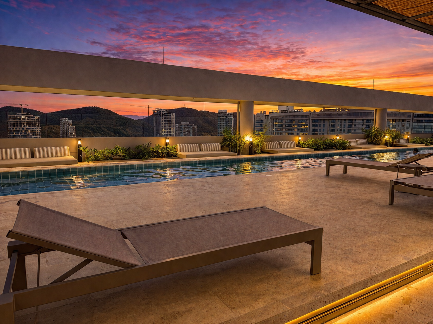 Piscina rooftop al atardecer con sillas lounge