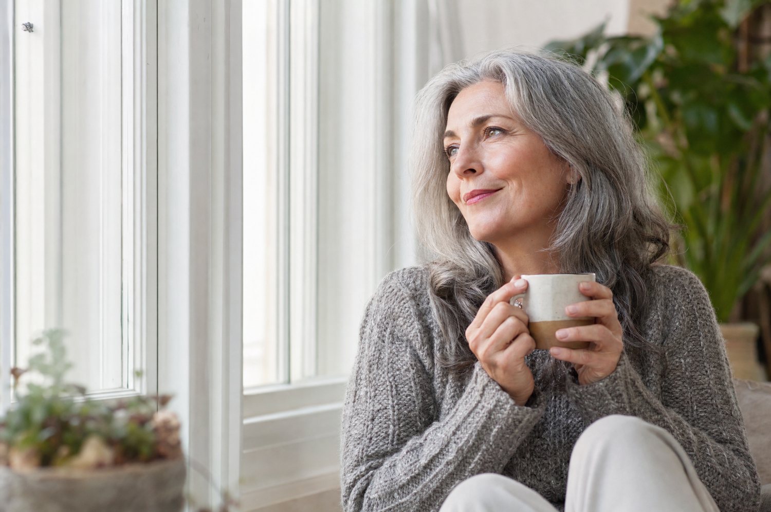 A woman in her fifties sitting quietly by a window