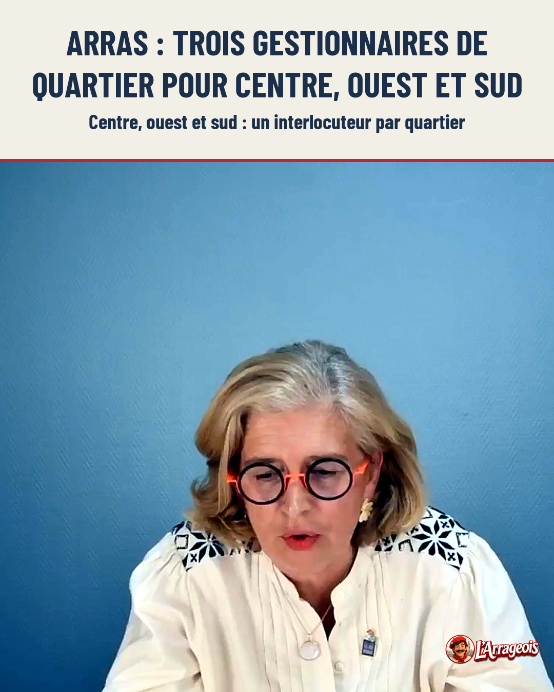 Une femme aux cheveux blonds, portant des lunettes à monture orange et une blouse blanche brodée, parle devant un fond bleu uni.