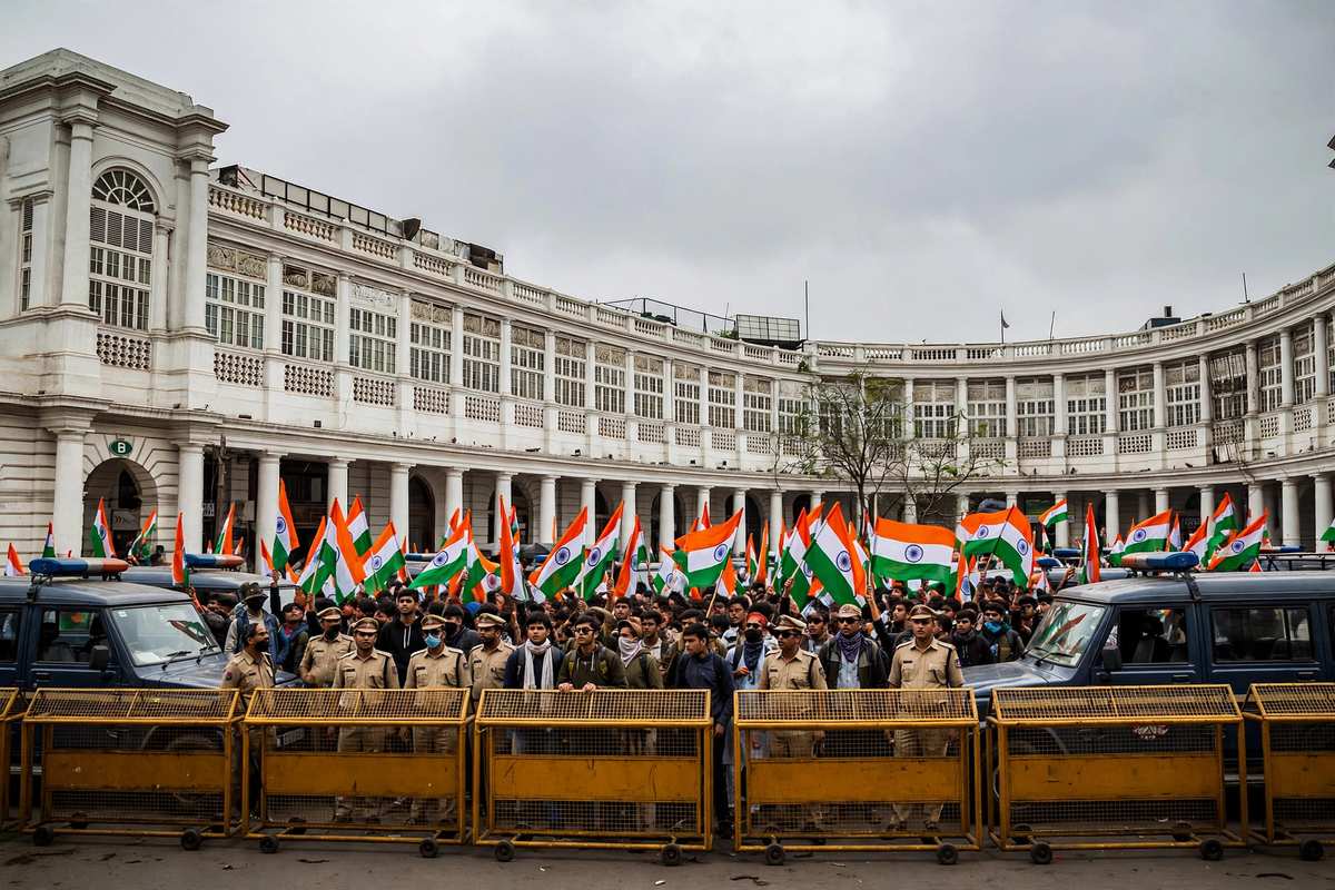 दिल्ली के कनॉट प्लेस के पास तिरंगा लिए प्रदर्शनकारी और पुलिस बैरिकेड