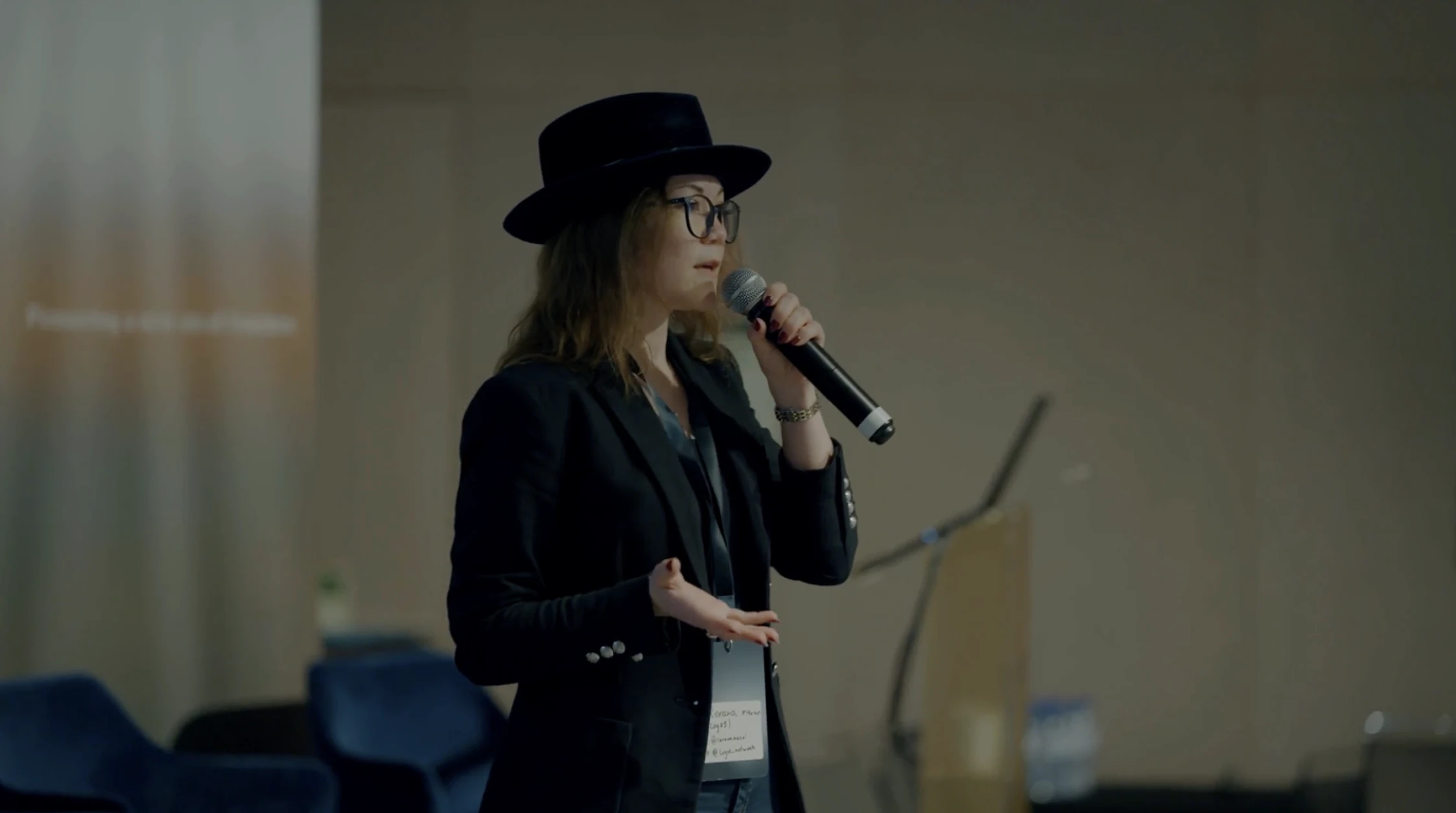 Female speaker wearing a black hat and blazer mid-talk at the IFT Lisbon stage