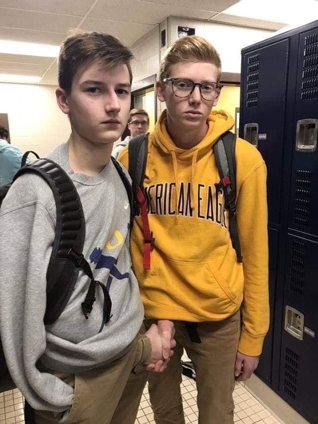Two teen guys shaking hands through their pants'fly