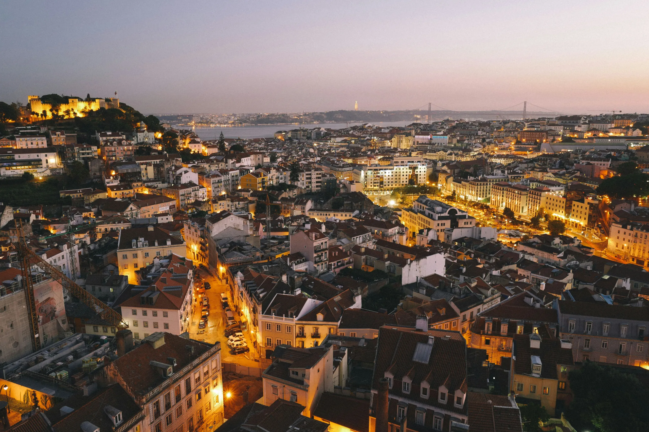 Sunset view across Lisbon's skyline with the castle silhouetted in warm light