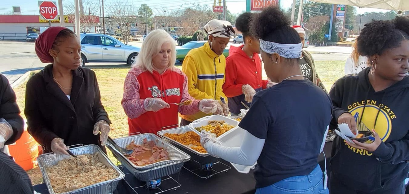 Volunteers serving a community meal outdoors in Douglas County