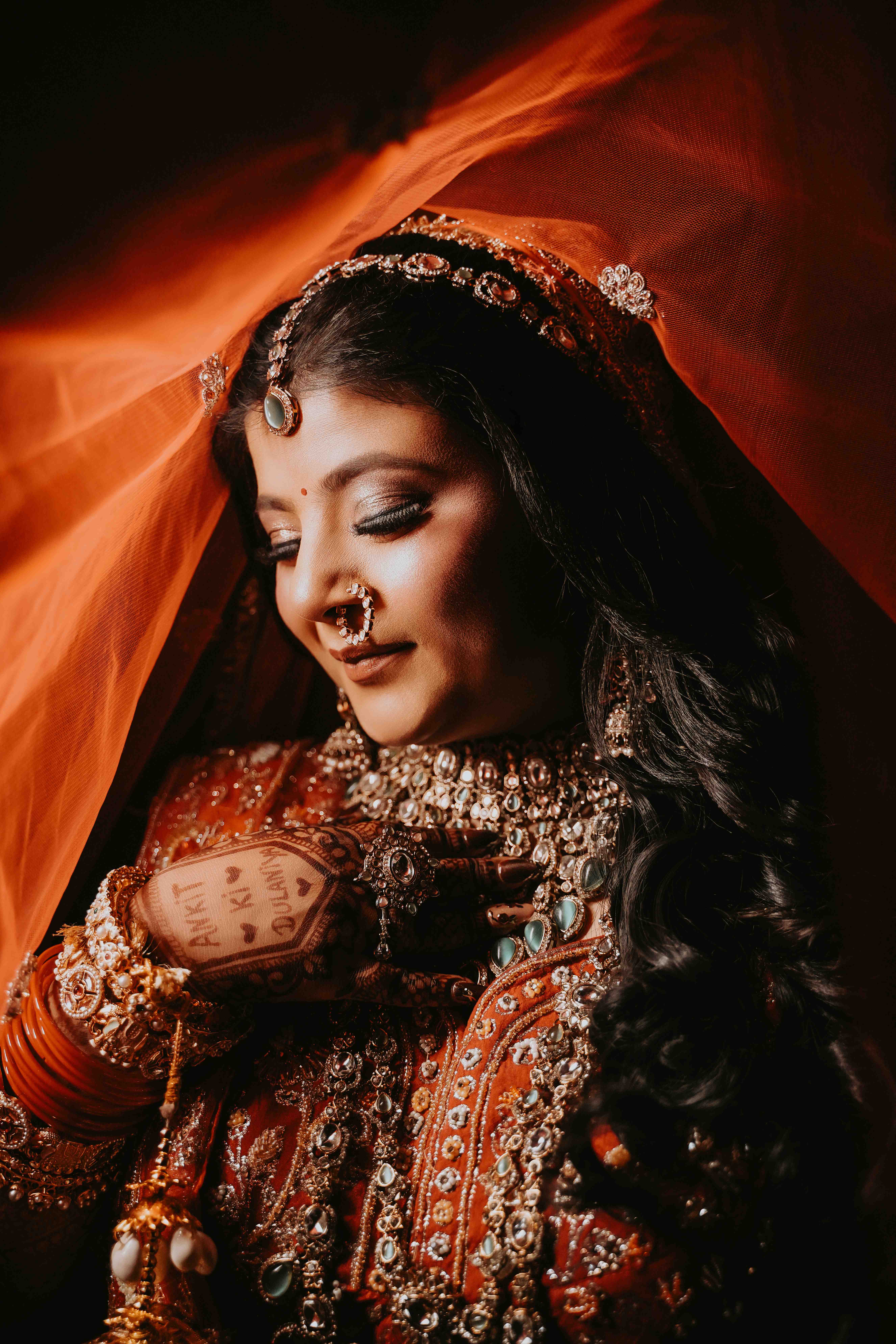 Intricate bridal mehendi henna hands adorned with gold jewellery bangles holding a small floral bouquet — Best Wedding Photography in Ludhiana detail shot