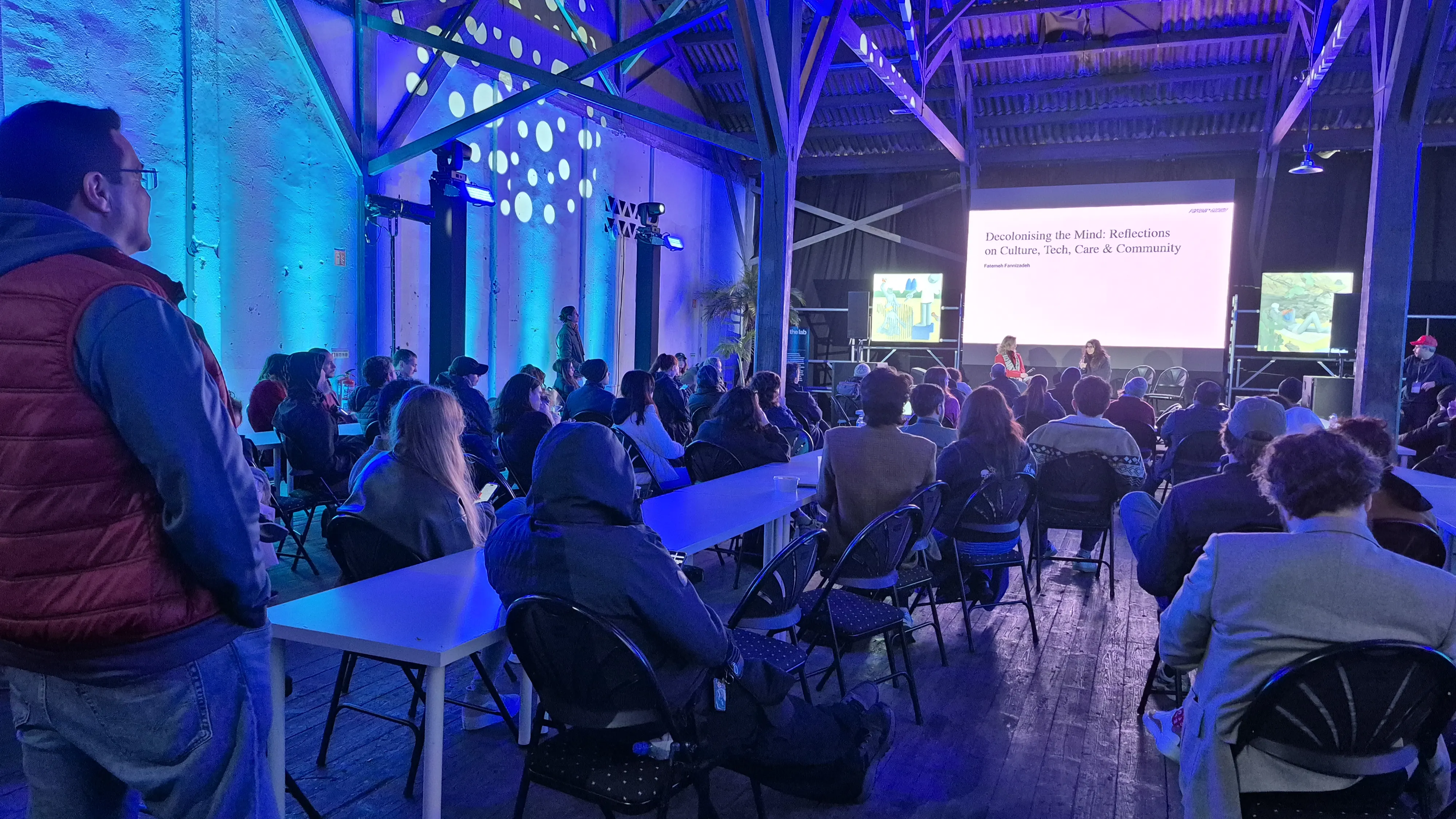 Evening festival event in a Lisbon warehouse with blue lighting and a seated audience