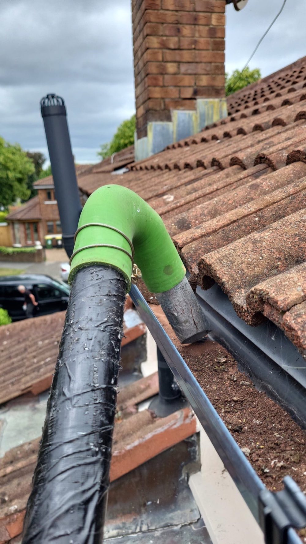 Gutter vacuum tube routed past a chimney flashing