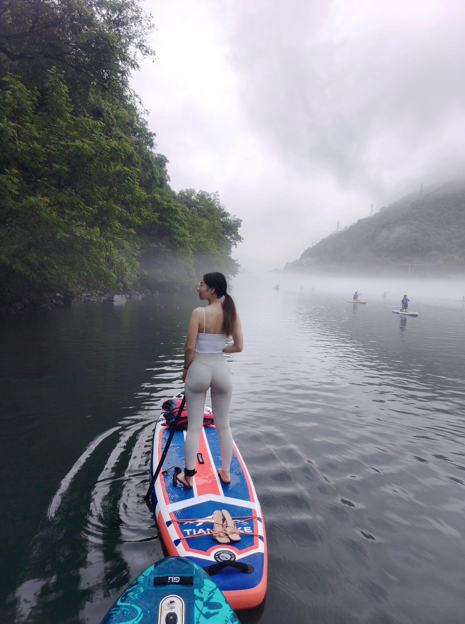 Phụ nữ yêu thể dục mặc trang phục quần yoga đứng trong hồ trên ván chèo