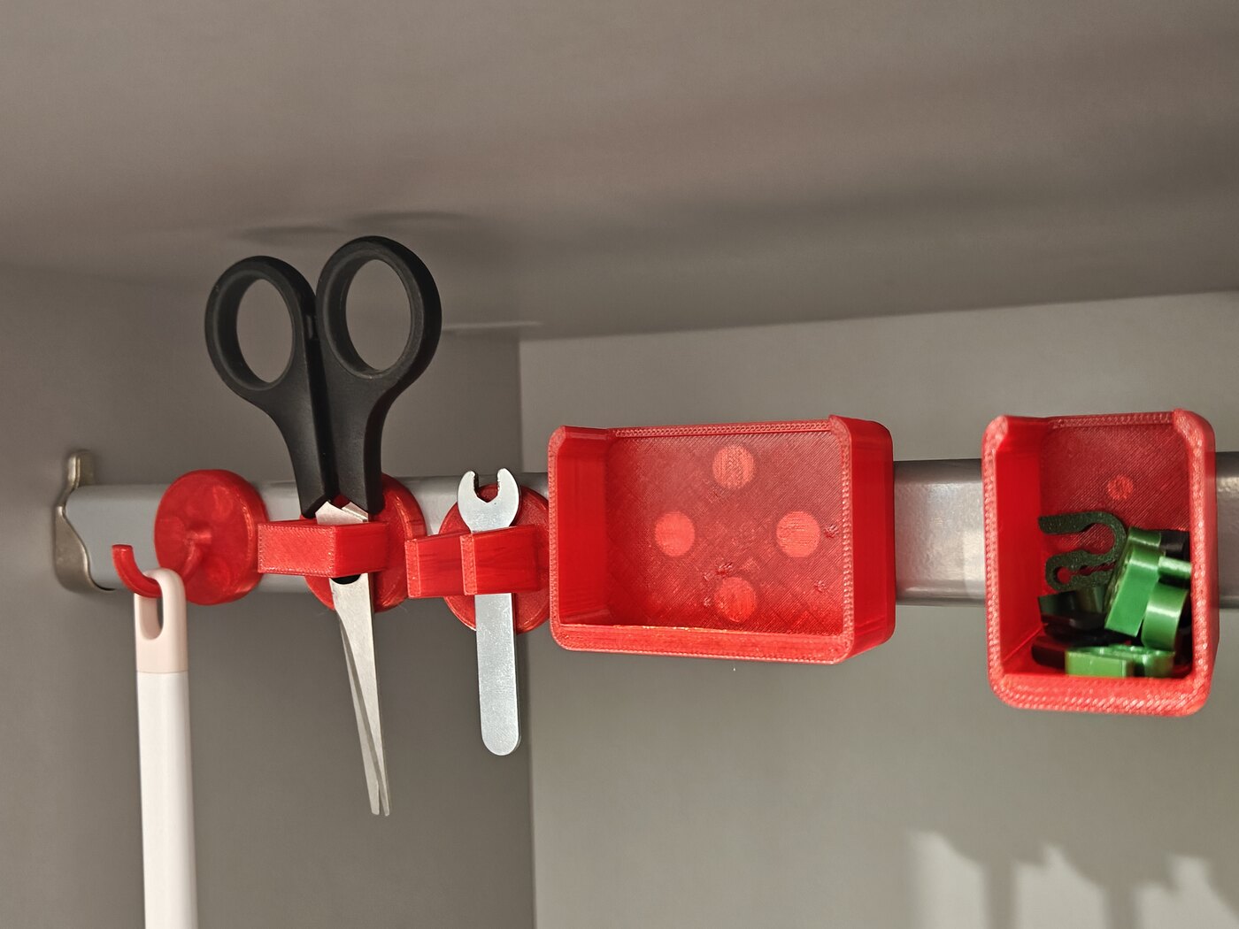 The MagDock family snapped onto a steel rail — hook, scissor slot, pliers slot, and trays, printed in red PLA