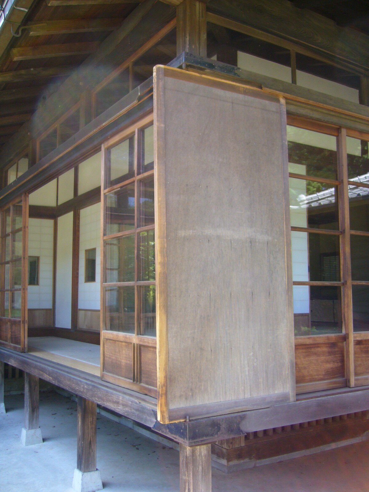 Traditional Japanese amado storm shutters adjacent to an engawa — the outer protective layer of a building's multi-layer climate envelope