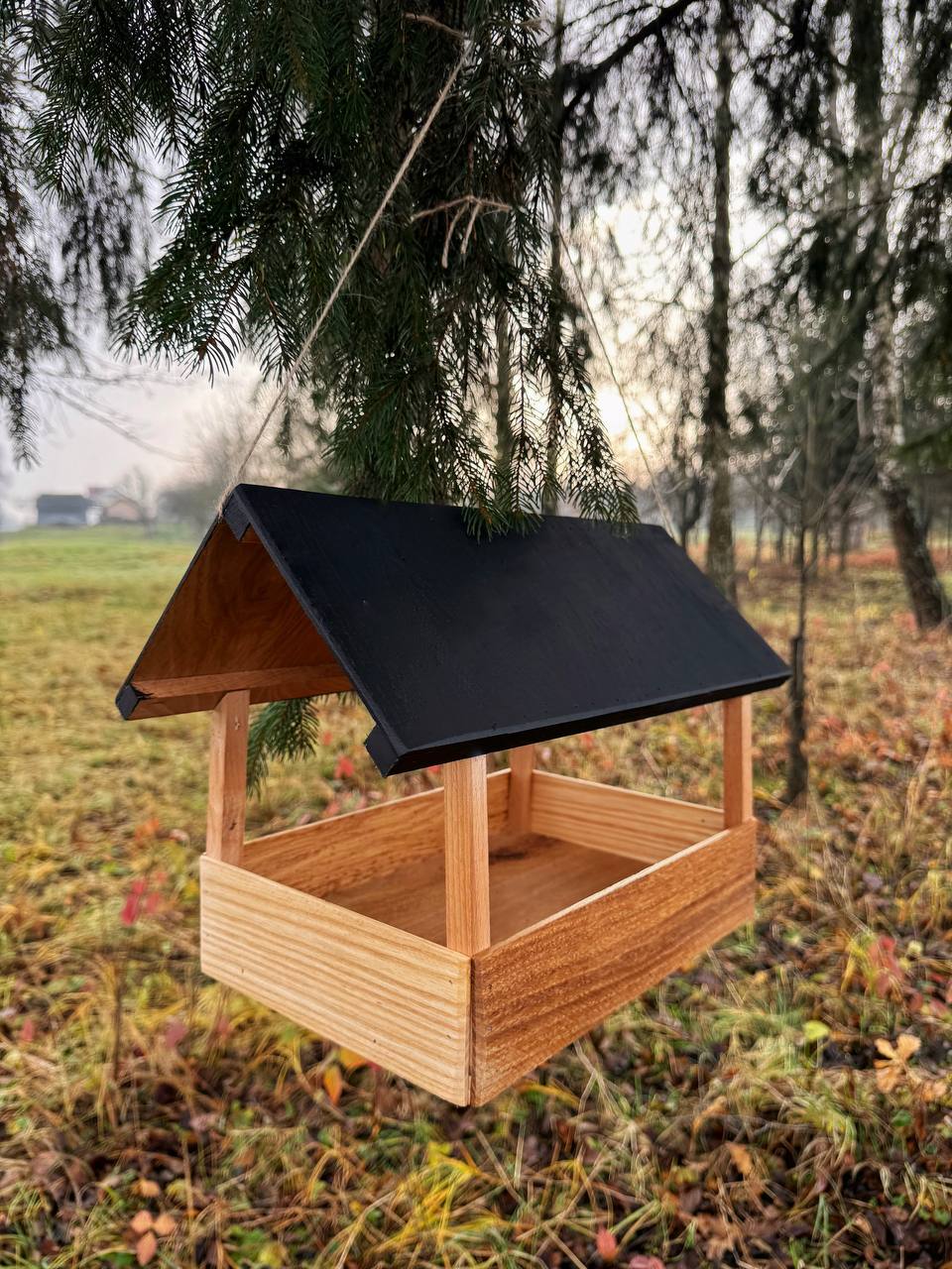 Пташка їсть з дубової годівнички