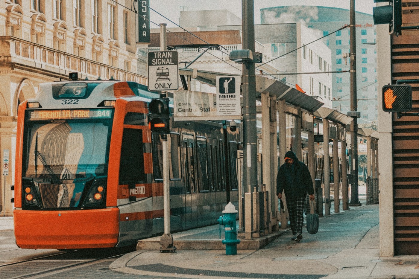 METRORail train traveling along a sunny street in downtown Houston.
