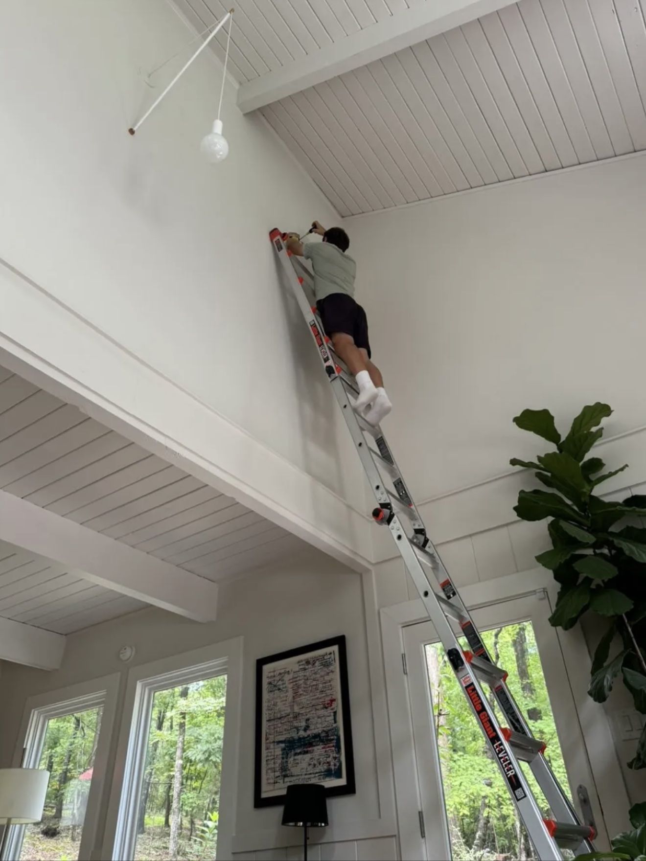 Aleh high on a long ladder, working near a vaulted ceiling