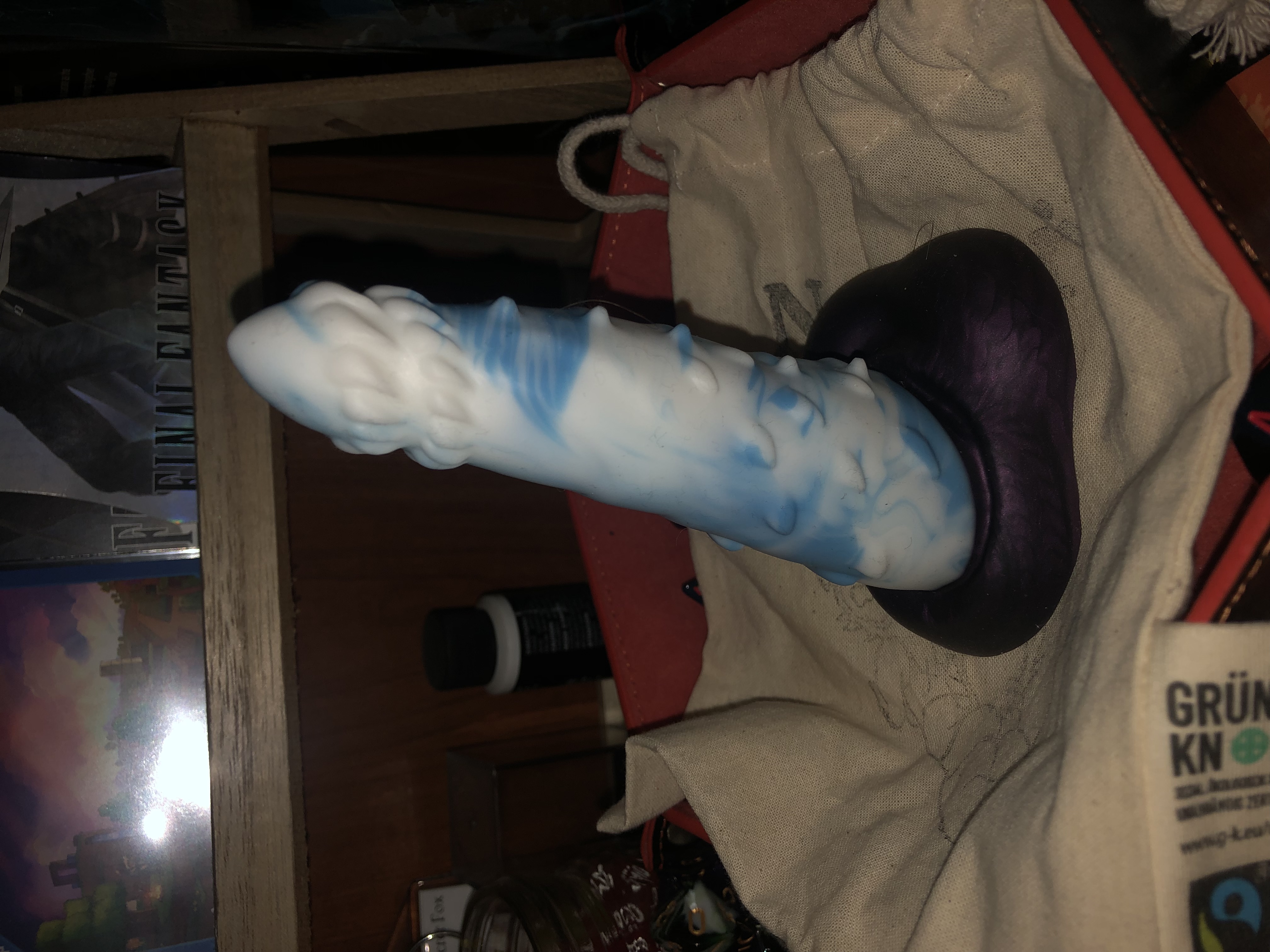 a photo of my custom finn in a leather dice tray. it is white and sky blue marbled with a near-black purple base.